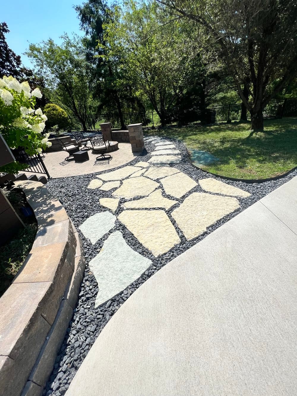 Stone pathway with decorative gravel and seating area in a landscaped yard.