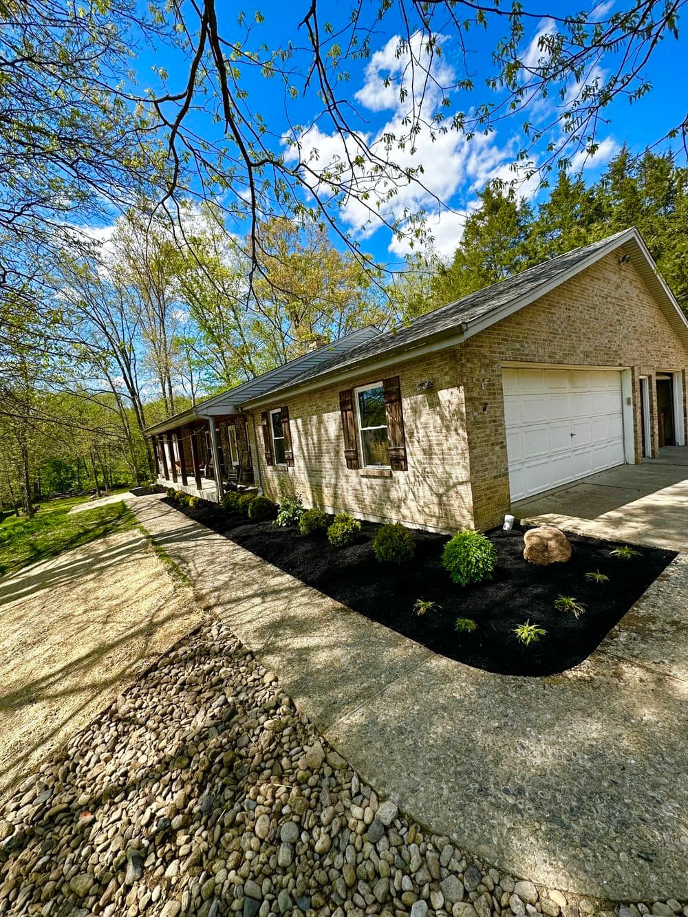 Modern brick house with landscaped yard, driveway, and clear blue skies. Ideal for serene living.